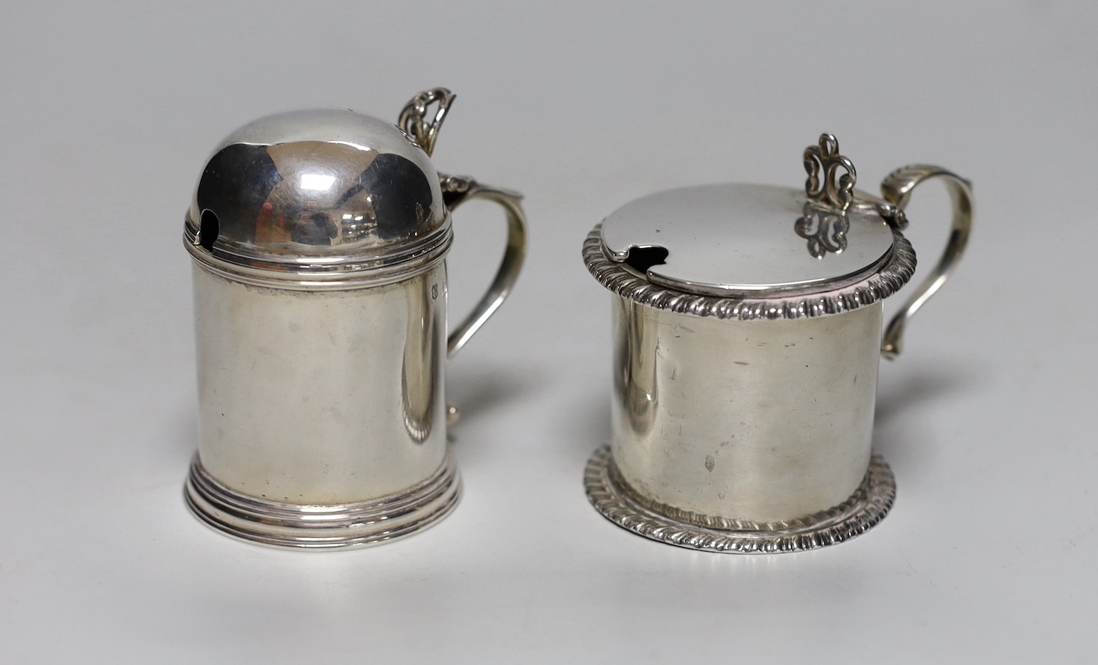 A late Victorian silver dome topped mustard pot, Josiah Williams & Co, London, 1897, height 8cm and an Edwardian silver drum mustard, London, 1902, 8.1oz, both with glass liners, one associated.